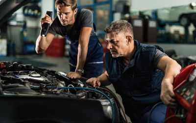 mechanics re-gassing a vehicle air con system