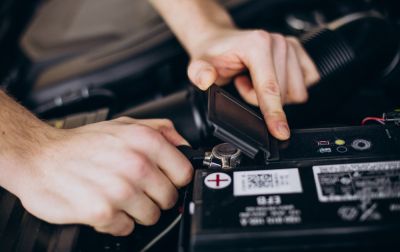 mechanic checking a battery terminal in a car