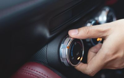person;s hand turning the aircon dial on a car